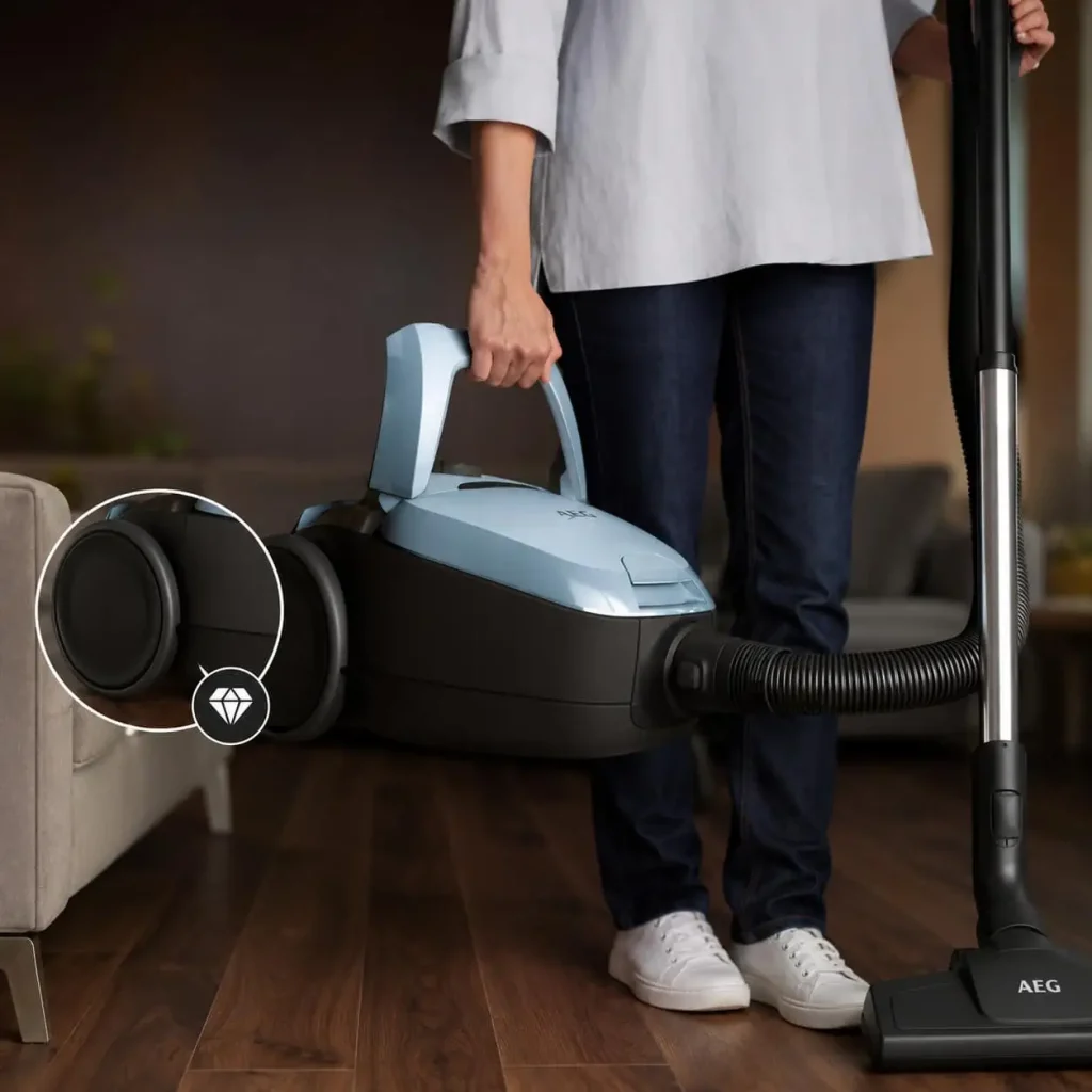 بلند کردن جاروبرقی آاگ مدل VX82-1-5DB توسط فرد که شلوار جین و لباس سفید دارد