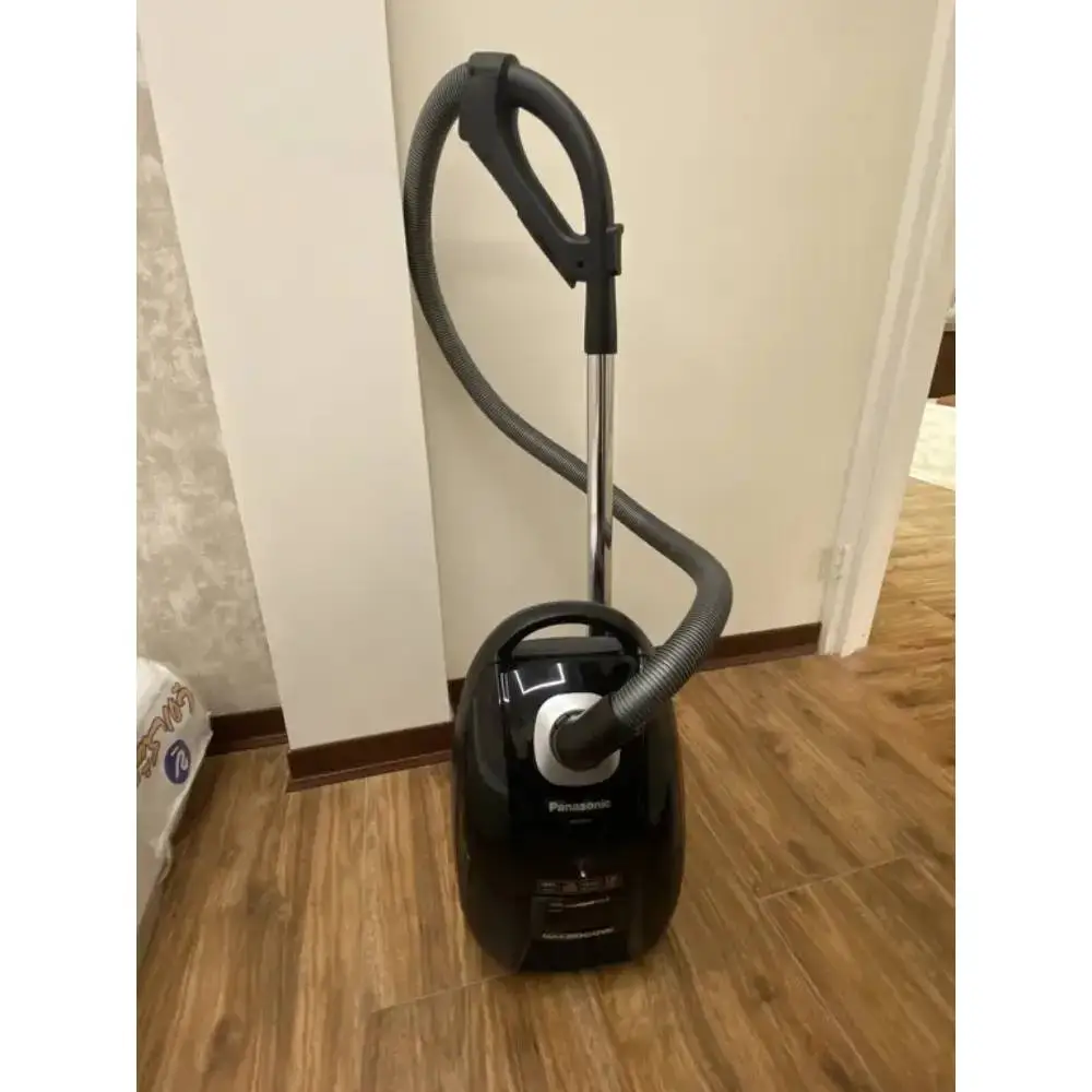 جاروبرقی پاناسونیک مدل MC-CG713 رنگ مشکی در حالت عمودی رو به رو به روی دیوار سفید