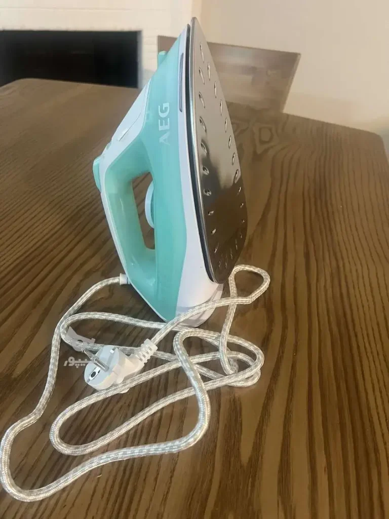 اتو بخار 2400 وات آ ا گ مدل DB1740LG به حالت ایستاده روی میز چوبی