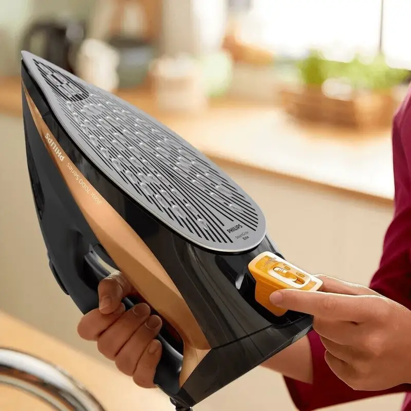 فرد در حال جا زدن مخزن زرد رنگ ضد رسوب اتو بخار 2800 وات فیلیپس مدل DST7040 است