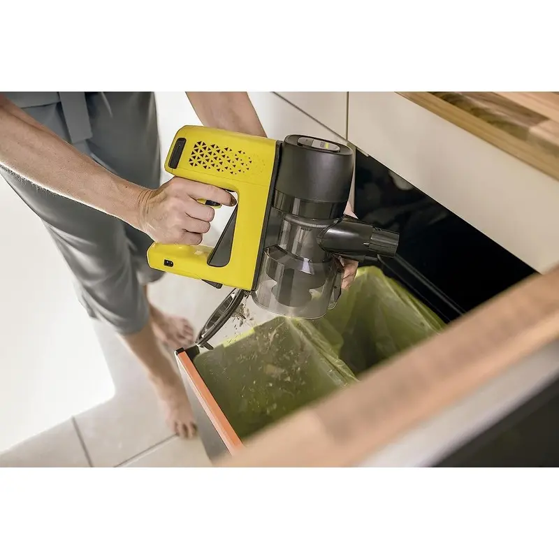 فرد در حالت تخلیه مخزن زباله جاروی شارژی کارچر مدل VC 4 CORDLESS MYHOME در سطح آشعال است