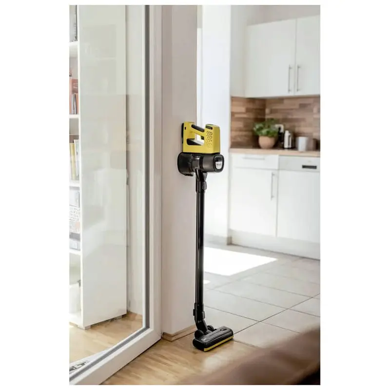 جاروی شارژی کارچر مدل VC 4 CORDLESS MYHOME زرد مشکی بر روی دیوار در حال شارژ