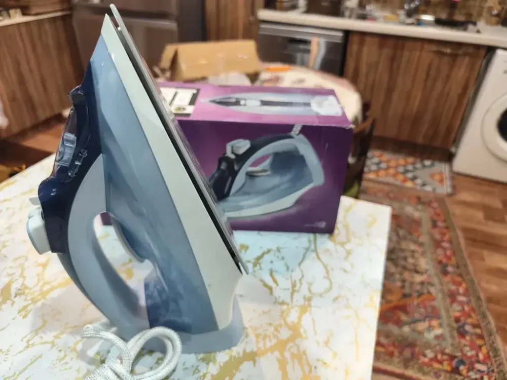 اتو بخار 2400 وات فیلیپس مدل DST5020 رنگ آبی در کنار کارتون بنفش خود